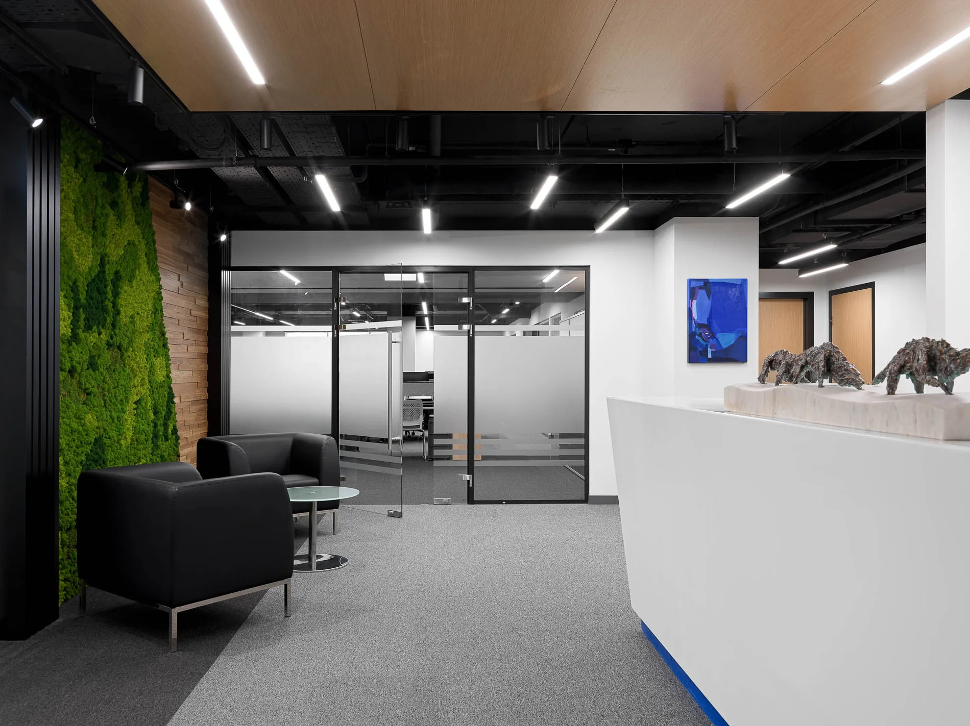 Recepción de una oficina en Moscú, Rusia, con pared vegetal, escultura y pintura azul.