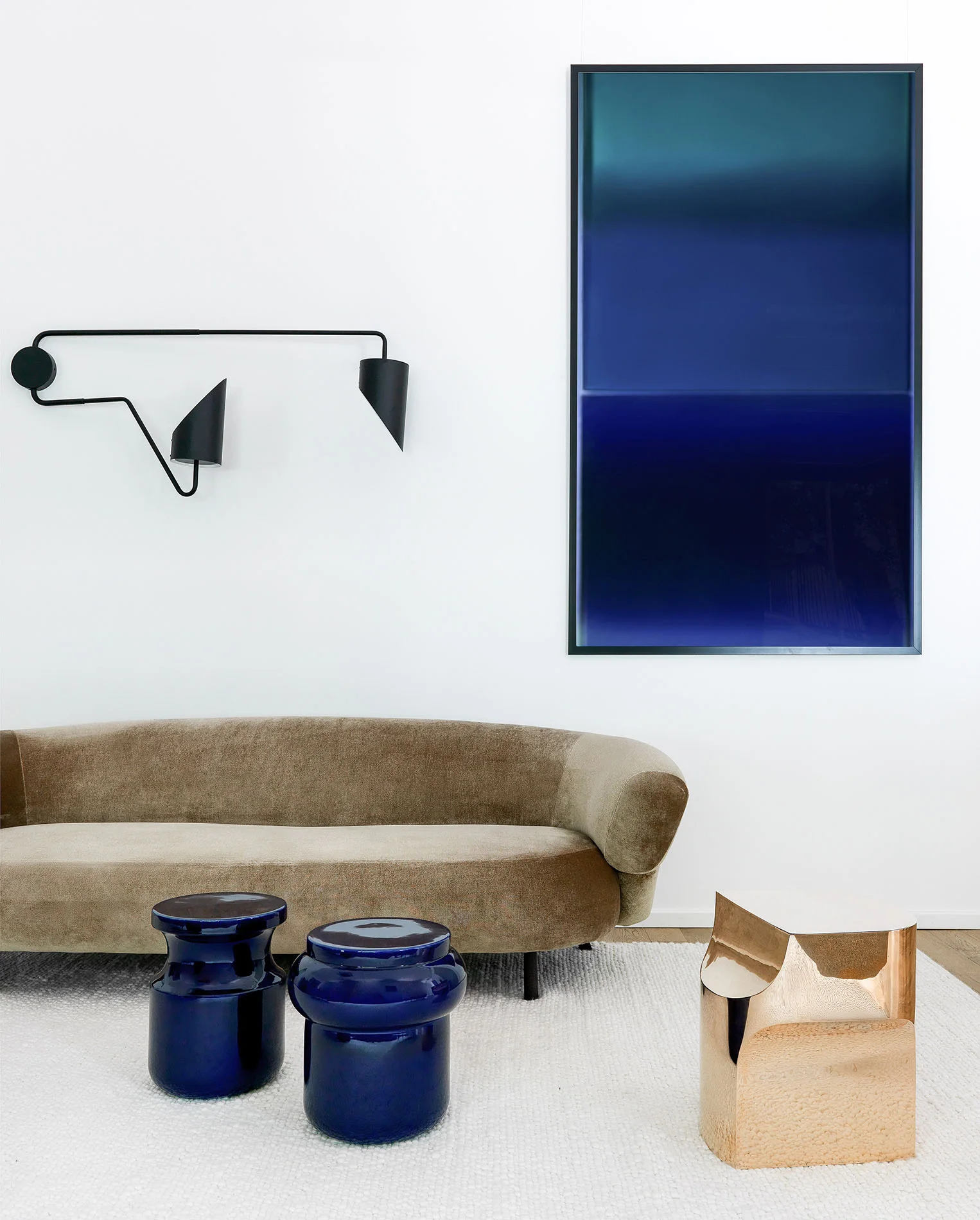 Rincón de un salón de belleza en Moscú con sofá curvo, mesas azules y una pintura abstracta azul.
