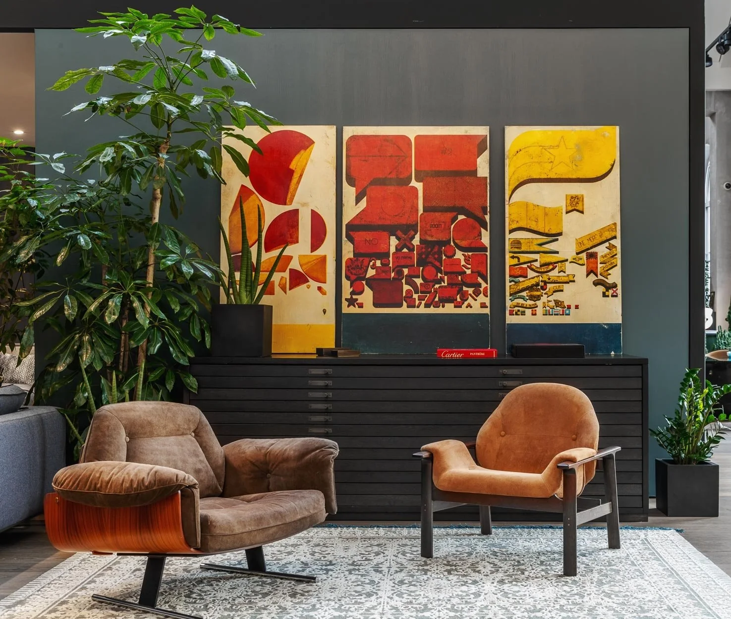 Showroom de diseño en Moscú, Rusia, con sillones de cuero, vegetación y tres obras gráficas de gran formato.