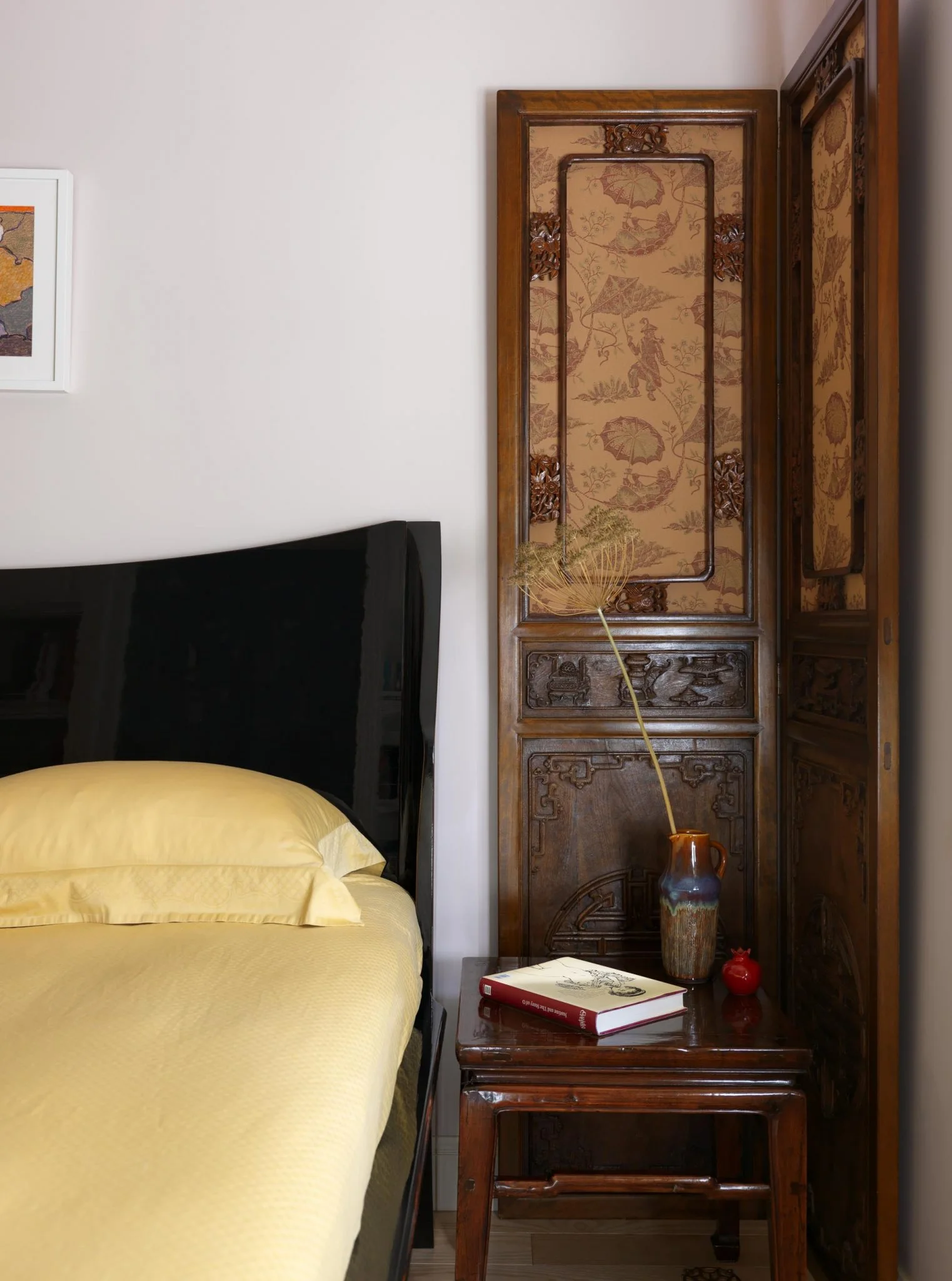 Dormitorio de un apartamento en Moscú con ropa de cama amarilla, biombo antiguo y mesa auxiliar.