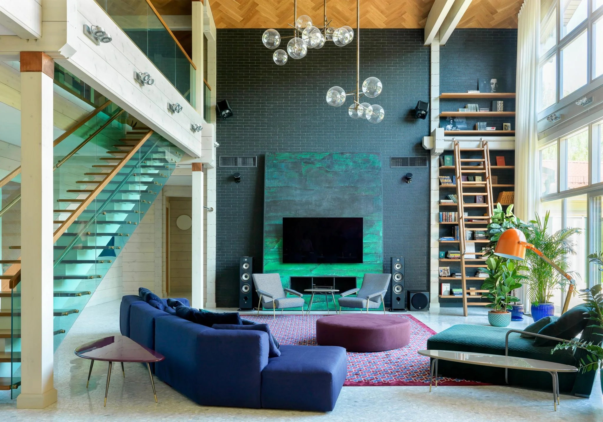 Sala de doble altura en Moscú con sofás azules, chimenea turquesa y escalera de vidrio.