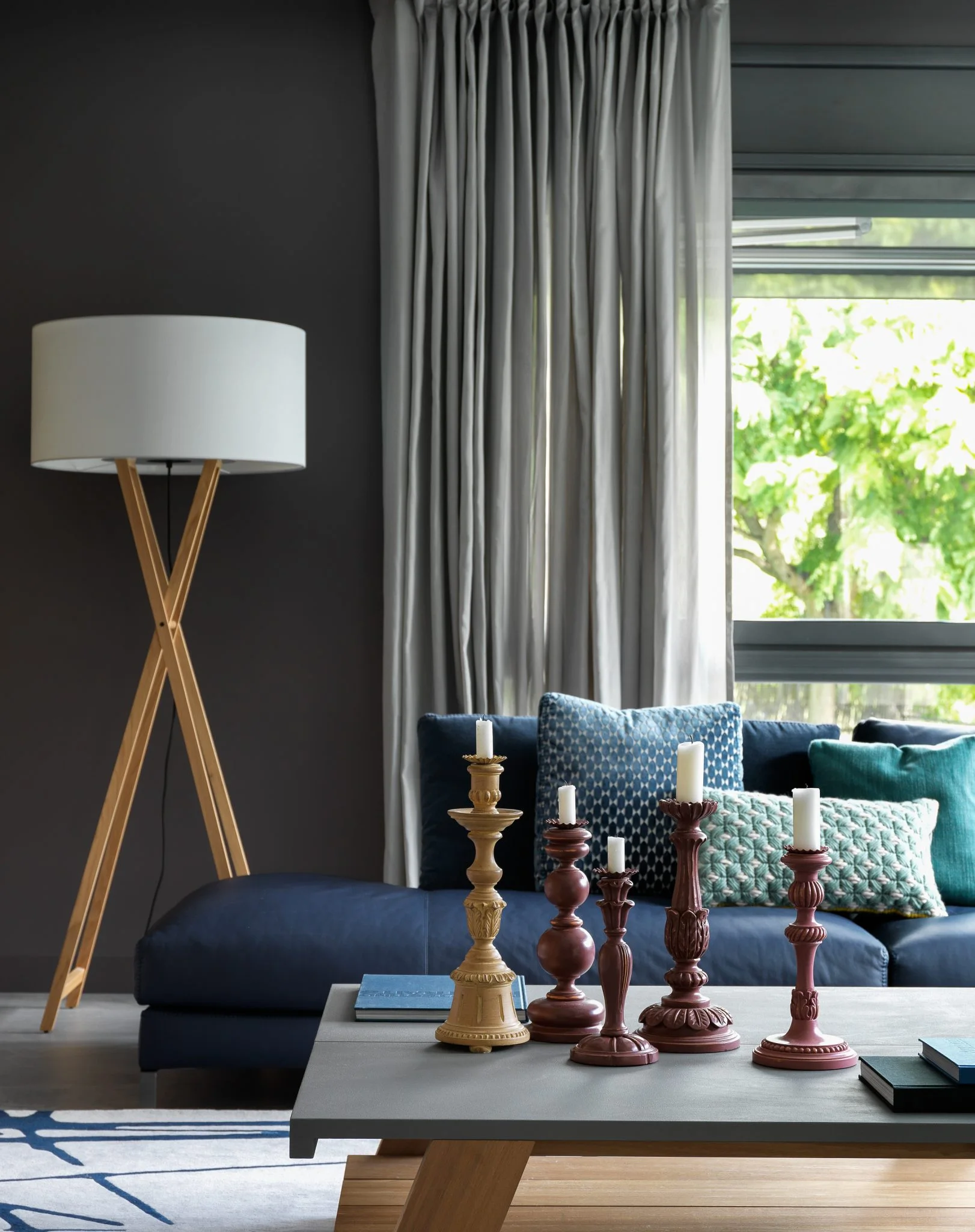Detalle de un salón en Barcelona con candelabros escultóricos, sofá azul y cortinas grises.